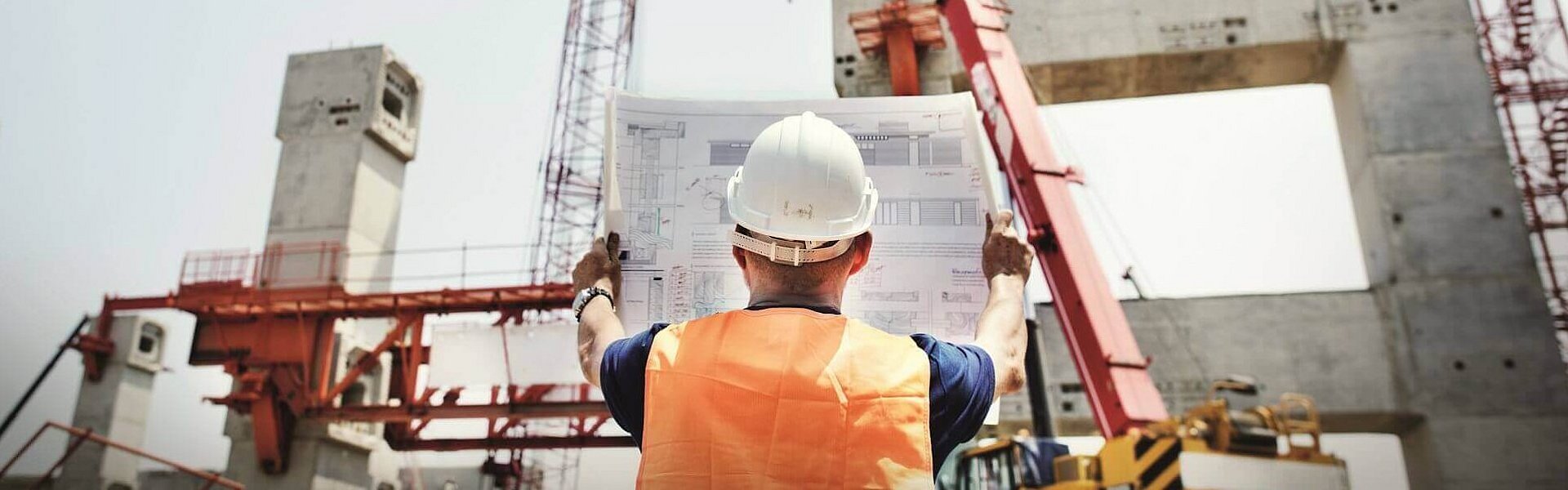 Baumeister mit Helm auf einer Baustelle mit Kran